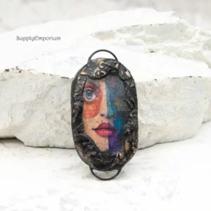 handmade polymer clay face connector pendant with two black iron loops and blue accents